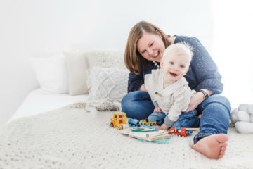 mom sits with son laughing and playing with toys