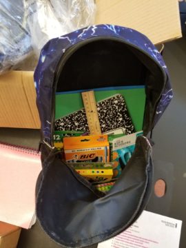 bookbag open with school supplies showing inside it