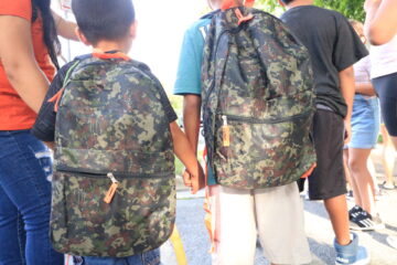 Children holding hands with their new backpacks at the Back2School Block Party.